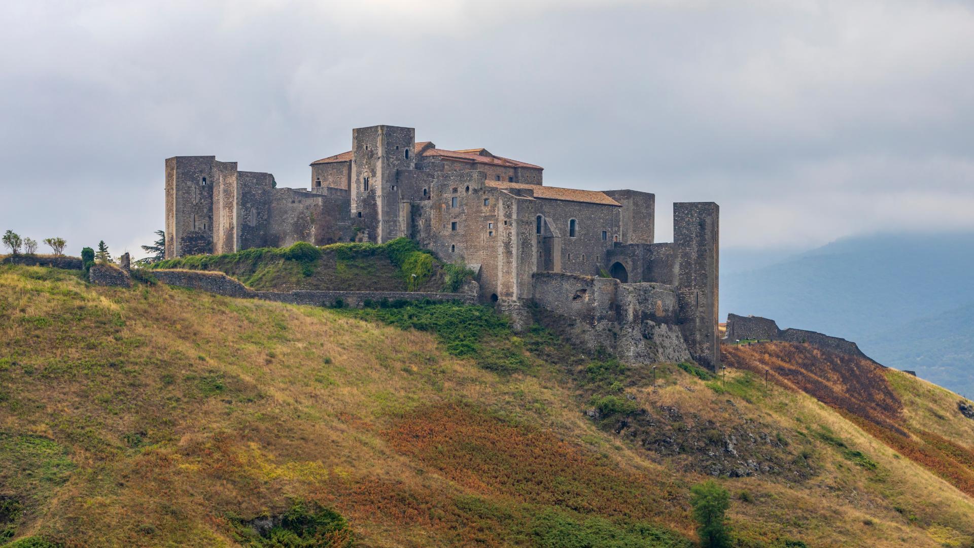 Maestoso castello medievale su collina, avvolto da un'atmosfera misteriosa e affascinante.