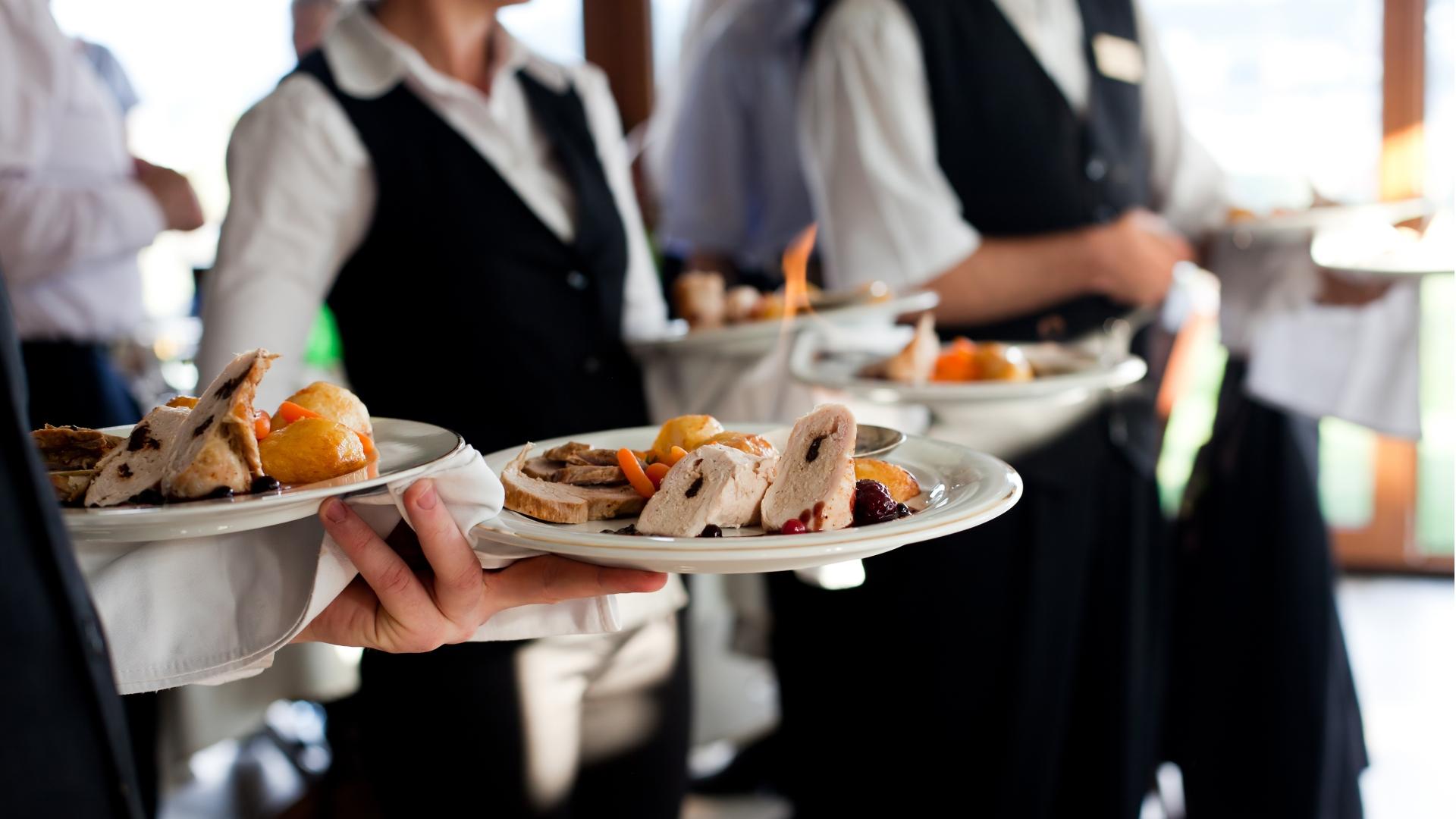 Camerieri eleganti servono piatti gourmet, atmosfera raffinata di un ristorante di lusso.