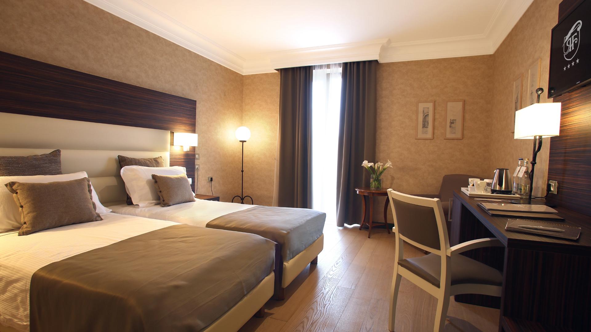 Camera d'albergo elegante con letti gemelli, scrivania e arredamento moderno.