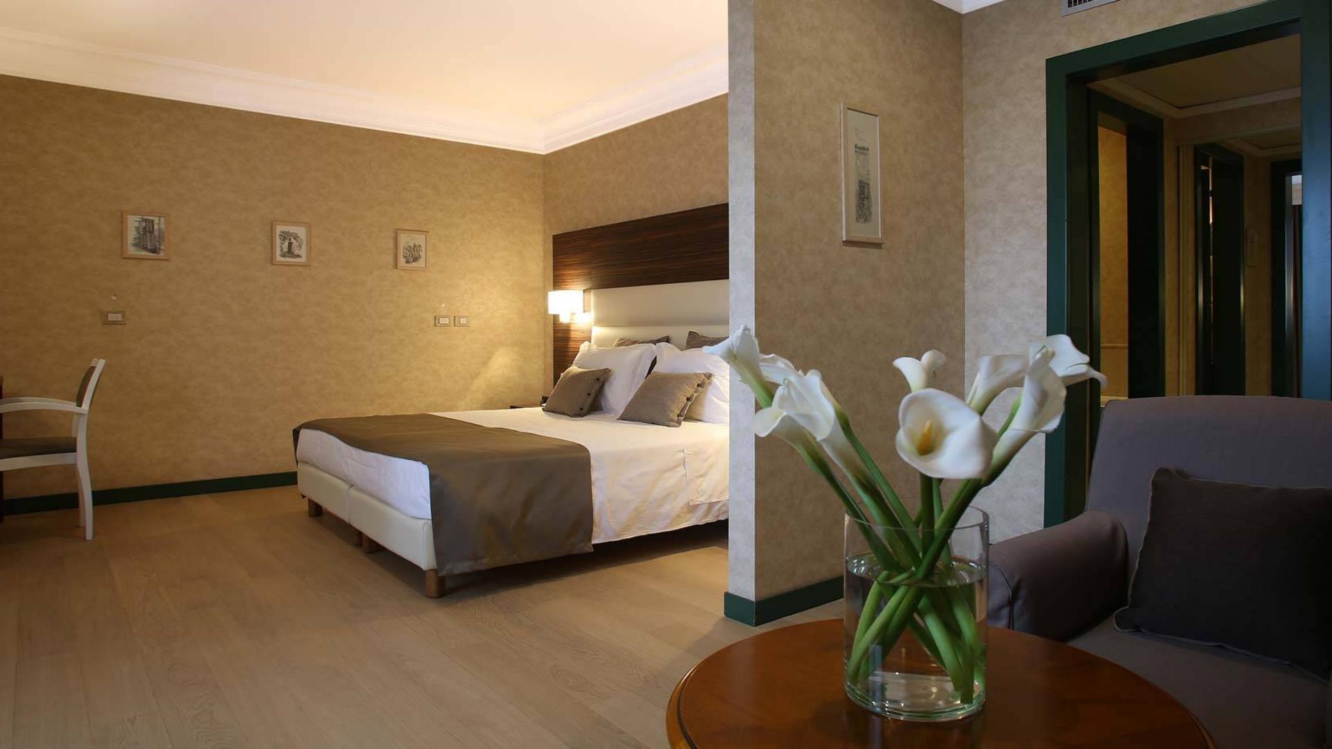 Camera elegante con letto matrimoniale, fiori freschi e arredamento accogliente.