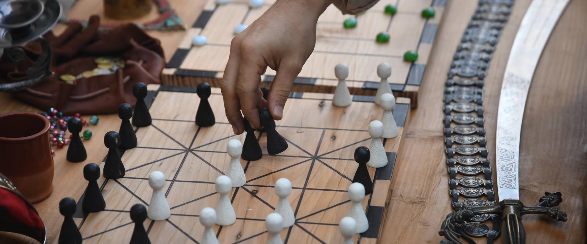 Gioco da tavolo con pedine bianche e nere, spada decorativa accanto.
