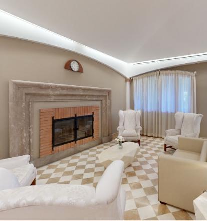 Salotto elegante con camino, poltrone bianche, atmosfera accogliente e rilassante.