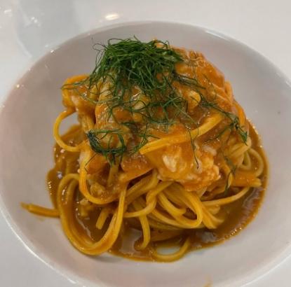 Spaghetti al sugo di granchio con finocchietto fresco, serviti in un piatto bianco.