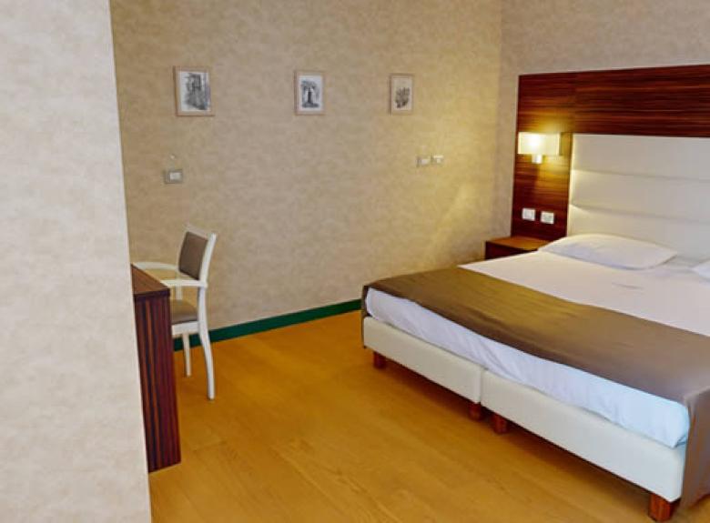 Camera d'albergo moderna con letto matrimoniale, scrivania e decorazioni minimaliste.