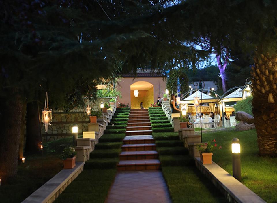 Viale illuminato al crepuscolo, atmosfera romantica con alberi e luci soffuse.