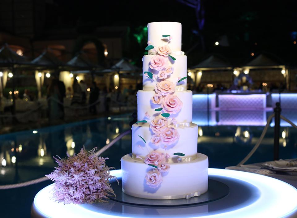 Torta nuziale a cinque piani, decorata con rose, illumina una serata elegante.