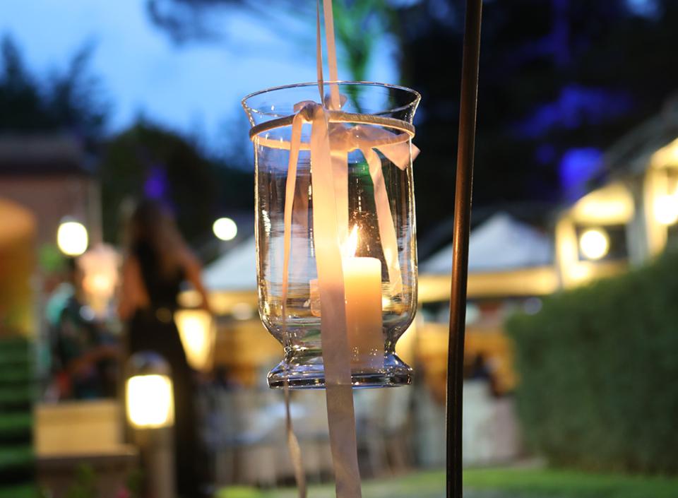 Candela sospesa in un giardino serale, atmosfera romantica e tranquilla.