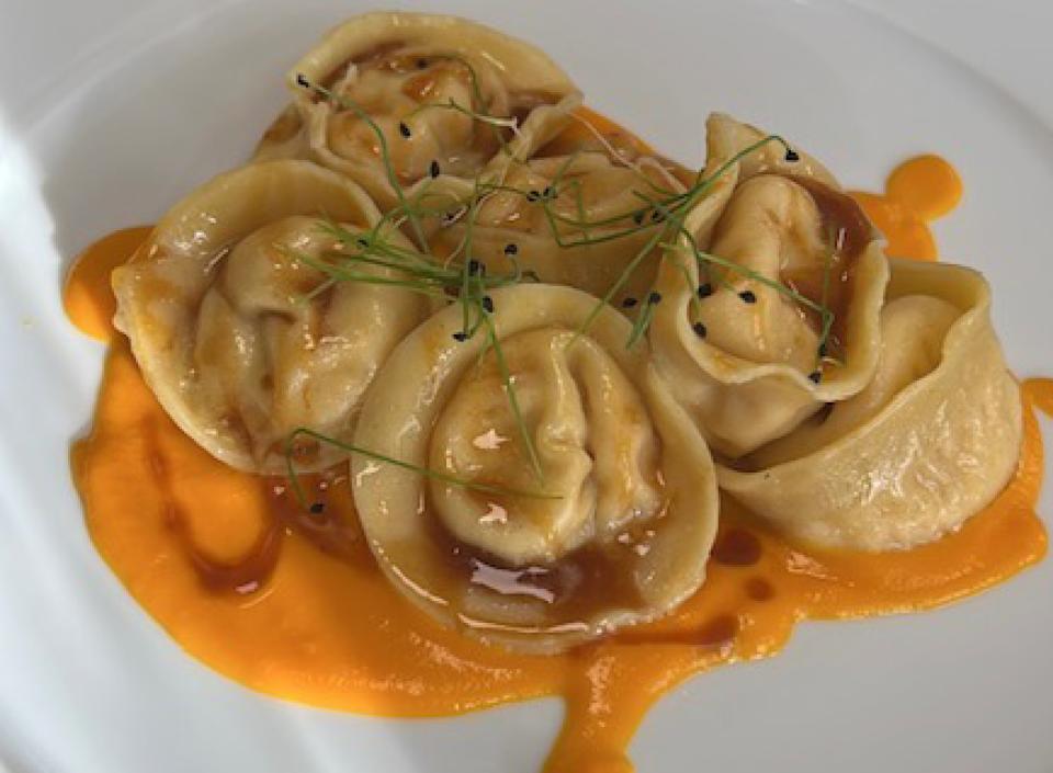 Orecchiette al sugo con verdure, servite su piatto bianco con erbe aromatiche.