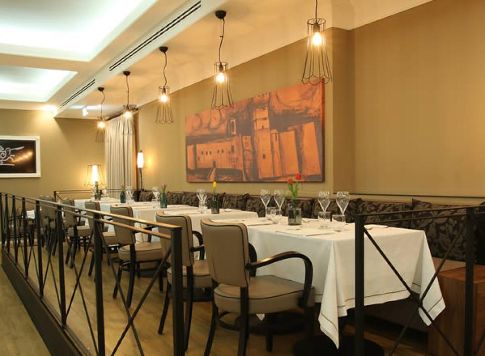 Ristorante elegante con tavoli apparecchiati, illuminazione soffusa e decorazioni artistiche alle pareti.
