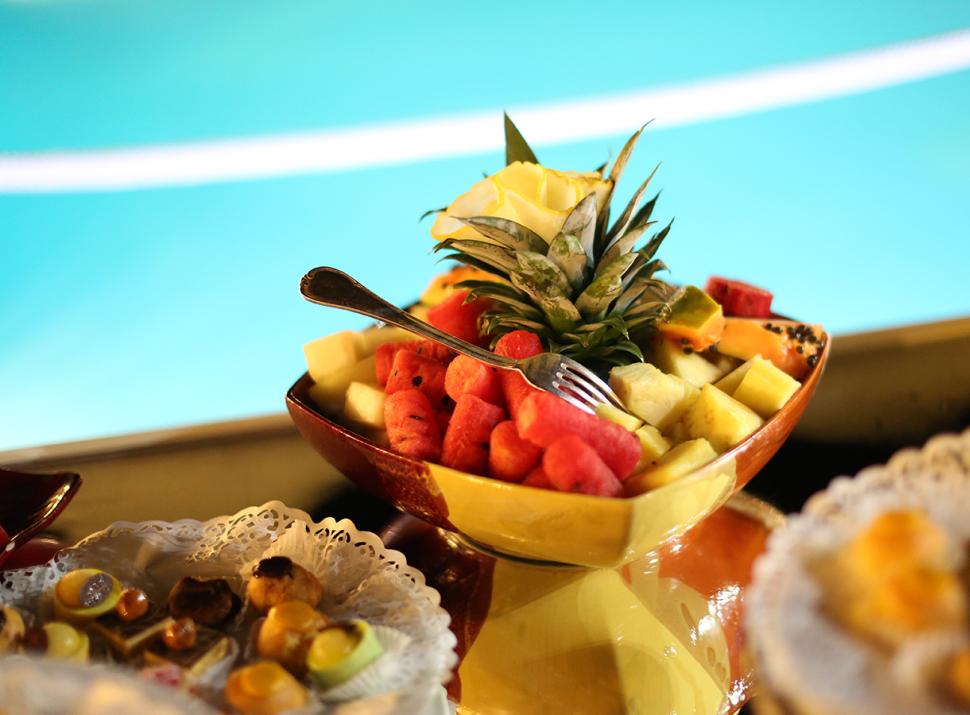 Frutta fresca colorata in una ciotola, con sfondo piscina. Atmosfera estiva e rinfrescante.