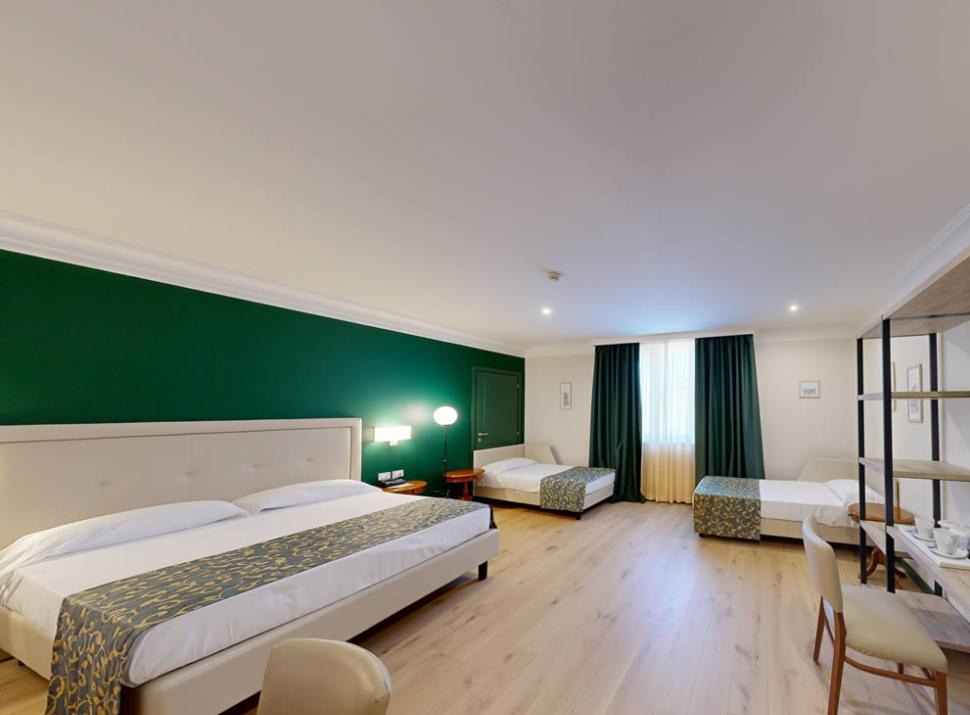 Camera spaziosa con letto matrimoniale e due letti singoli, arredamento moderno.