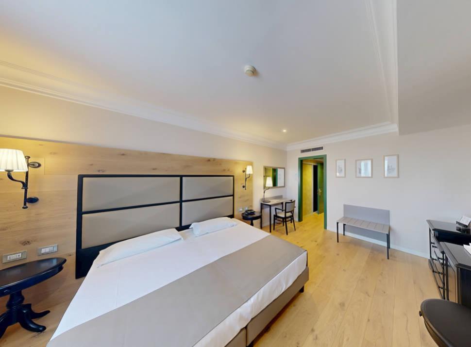 Camera moderna con letto matrimoniale, scrivania, e arredamento minimalista.