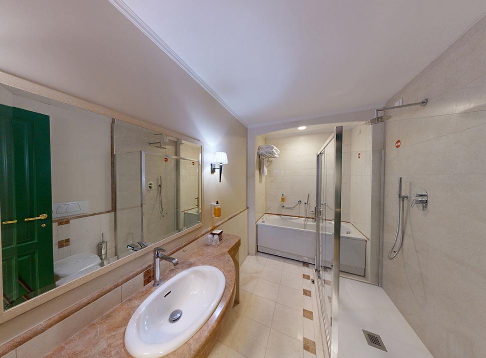 Bagno elegante, ampio specchio, lavandino moderno, doccia spaziosa, vasca accogliente, atmosfera lussuosa.